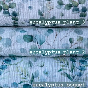 May include: Five rolls of white fabric with a watercolor eucalyptus leaf print. The fabric is labeled "meadow 2", "eucalyptus plant 3", "eucalyptus plant 2", "eucalyptus bouquet", and "eucalyptus plant".