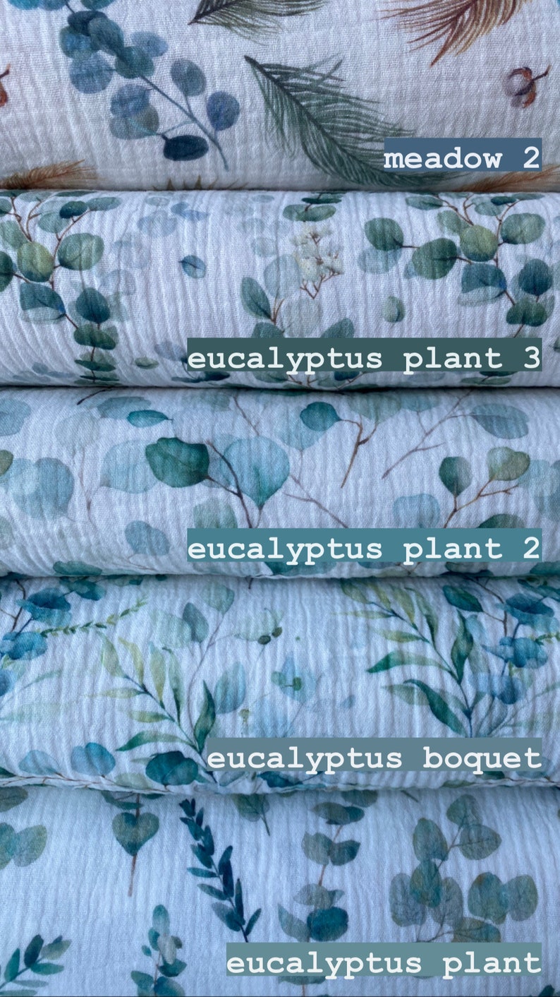 May include: Five rolls of white fabric with a watercolor eucalyptus leaf print. The fabric is labeled "meadow 2", "eucalyptus plant 3", "eucalyptus plant 2", "eucalyptus bouquet", and "eucalyptus plant".