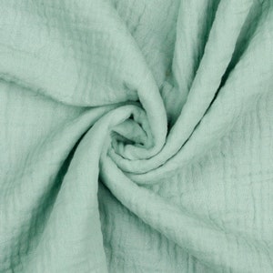 May include: A soft, light green fabric with a crinkled texture. The fabric is folded and draped, creating a soft and flowing look.