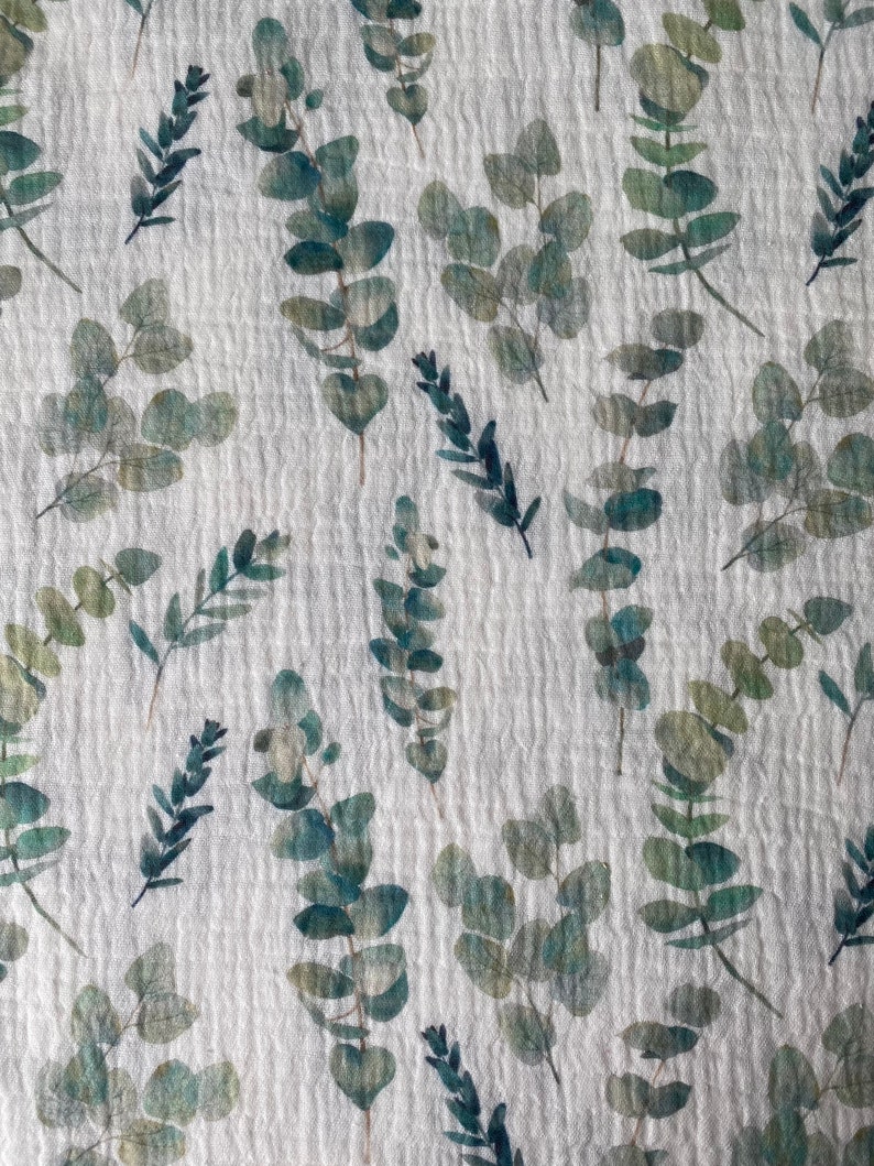 May include: White fabric with a repeating pattern of green eucalyptus leaves. The leaves are watercolor-style and have a slightly faded look.