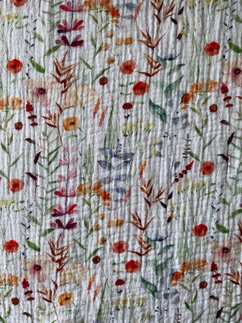May include: White fabric with a floral pattern featuring various shades of red, orange, yellow, and green. The flowers are stylized and resemble watercolor paintings.