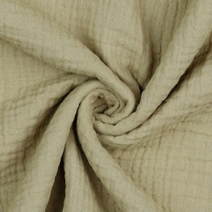 May include: A close-up of a soft, crinkled, light green fabric. The fabric is folded and twisted, showing its texture.