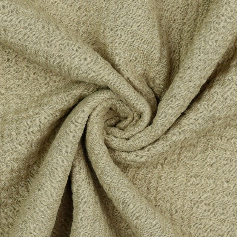 May include: A close-up of a soft, crinkled, light green fabric. The fabric is folded and twisted, showing its texture.