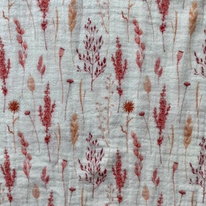 May include: A white fabric with a repeating pattern of pink and brown pressed flowers. The flowers are various types of grasses and wildflowers.