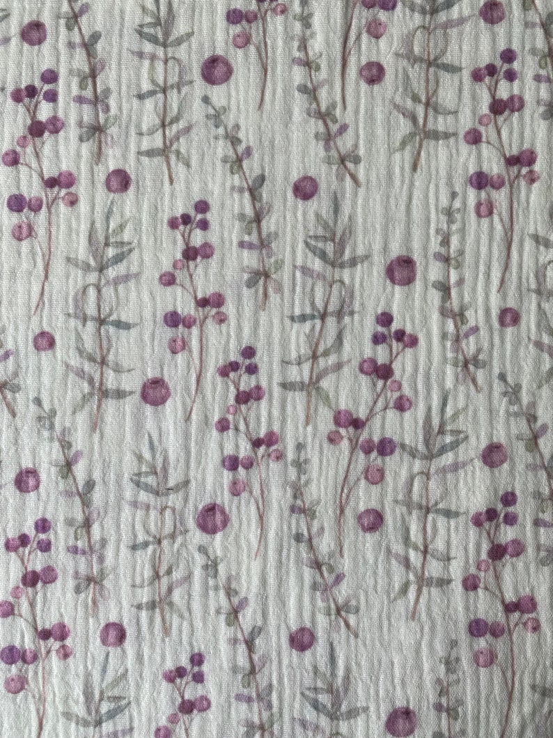 May include: A white fabric with a repeating pattern of small purple flowers and leaves. The fabric has a subtle texture.