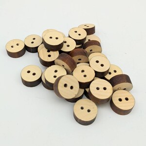 May include: A pile of wooden buttons with two holes each. The buttons are a light brown colour with a darker brown edge.