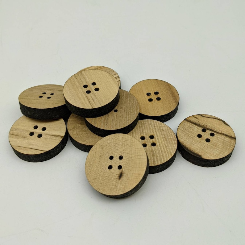 May include: A group of eight wooden buttons, each with four holes. The buttons are a light brown colour with a darker brown grain pattern.