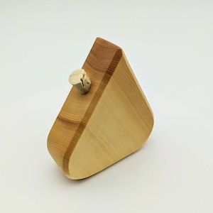 May include: A wooden object shaped like a triangle with a small, round, light brown cork protruding from the top.