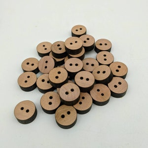 May include: A pile of wooden buttons with two holes each. The buttons are a light brown colour with a dark brown edge.
