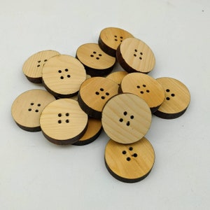 May include: A pile of wooden buttons, each with four holes. The buttons are light brown and have a natural wood finish.