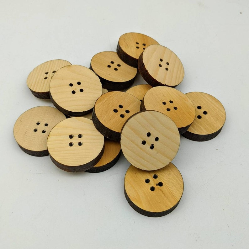 May include: A pile of wooden buttons, each with four holes. The buttons are light brown and have a natural wood finish.