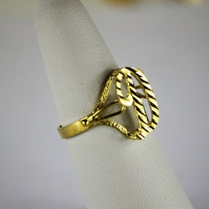 May include: A gold ring with a textured design in the shape of the number nine.