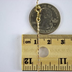Puede incluir: Un collar de cadena de oro con cierre de langosta, medido con una regla y una moneda de 25 centavos de d&oacute;lar estadounidense. La cadena mide aproximadamente 5 cm de largo.