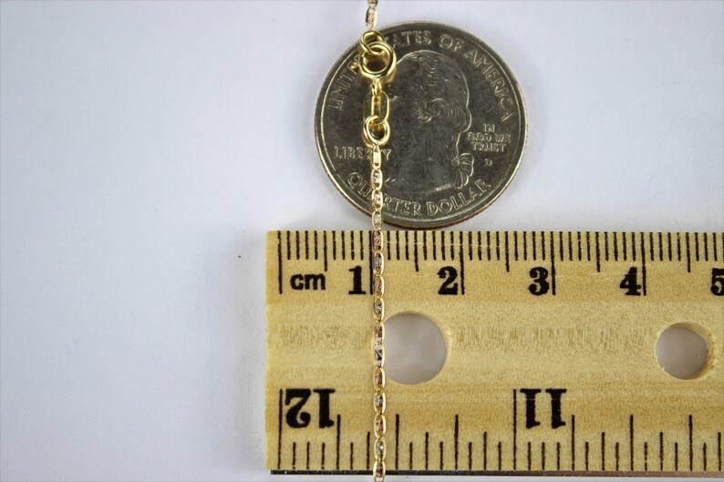Puede incluir: Un collar de cadena de oro con cierre de langosta, medido con una regla y una moneda de 25 centavos de d&oacute;lar estadounidense. La cadena mide aproximadamente 5 cm de largo.