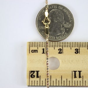 Puede incluir: Un collar de cadena de oro con cierre de langosta, medido con una regla y una moneda de 25 centavos de d&oacute;lar estadounidense. La cadena mide aproximadamente 5 cm de largo.