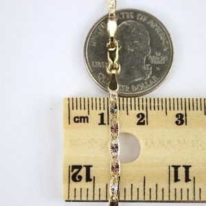 Puede incluir: Un collar de cadena de oro con un cierre, medido con una regla y una moneda de un cuarto de d&oacute;lar estadounidense. La cadena mide aproximadamente 5 cm de largo.