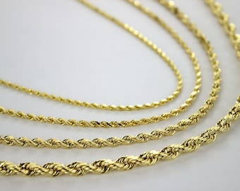 May include: Four gold rope chains of different thicknesses, arranged in a layered pattern on a white background.