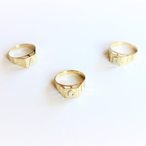 May include: Three gold rings with a different letter on each. The letters are A, G, and D.