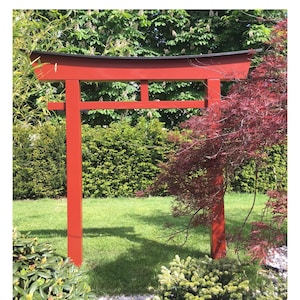 Pu&ograve; includere: Un torii in legno rosso, un tradizionale portale giapponese, si erge in un giardino. Il torii &egrave; fatto di legno e ha una parte superiore nera. Il torii &egrave; circondato da vegetazione verde e da un acero rosso.