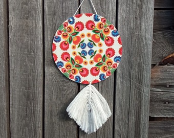 Ronde, levendig gekleurde boho-stijl wanddecoratie met macrame, roodblauwe volksbloemen op witte achtergrond, Poolse volkskunst modern ornament