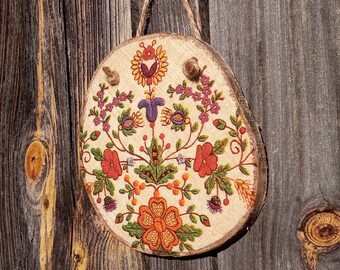 Decoration on a wood slice with symmetrical wild flowers stylized as folk embroidery, country house cottagecore aesthetics, Floral folk art