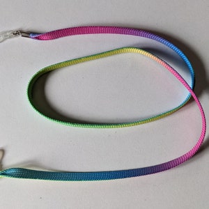 May include: A multi-coloured glasses strap with clear plastic loops and silver-tone metal clasps. The strap fades from blue to green, yellow, and pink. The strap is designed to hold spectacles.