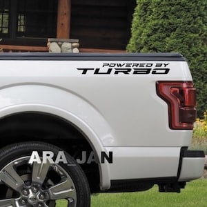 May include: White pickup truck with a black "Powered by Turbo" decal on the side. The truck has a black bumper and a black wheel.