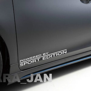 May include: A black car with a white "Powered by Sport Edition" decal on the side.