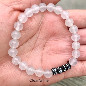 May include: A white beaded bracelet with black letter beads spelling out "WWJD".