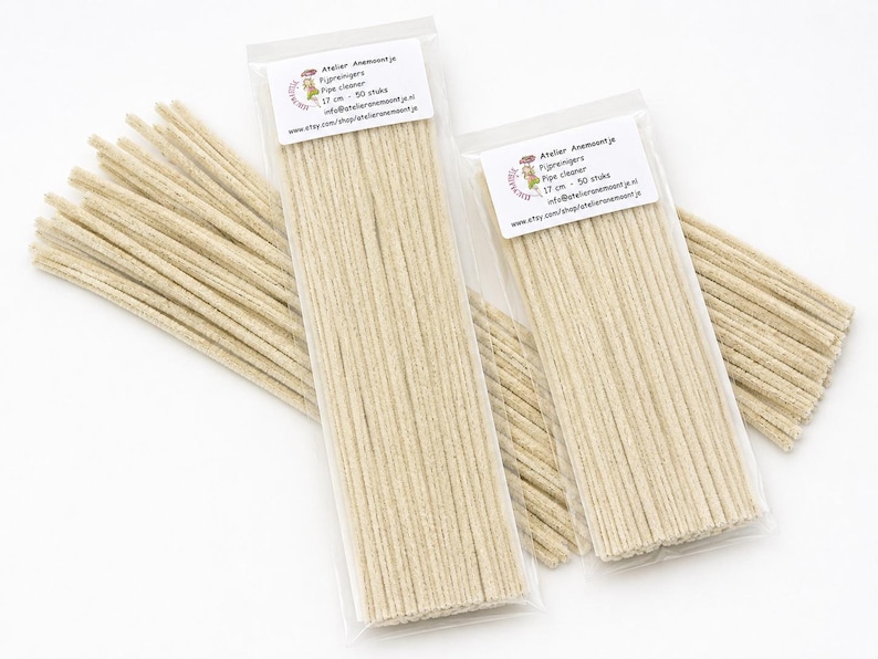 May include: Two clear plastic bags containing beige pipe cleaners, each labeled with Atelier Anemoontje, 17 cm, and 50 stuks. The pipe cleaners are long, thin, and fuzzy, arranged in parallel rows within the packaging for craft use.