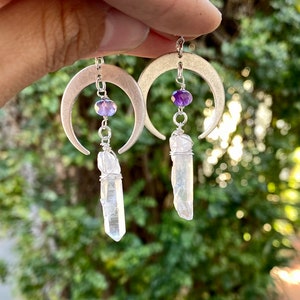 Pu&ograve; includere: Orecchini a forma di mezzaluna d'argento con perline di ametista e gocce di cristallo di quarzo trasparente.