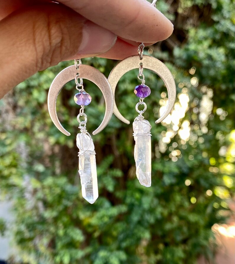 Pu&ograve; includere: Orecchini a forma di mezzaluna d'argento con perline di ametista e gocce di cristallo di quarzo trasparente.