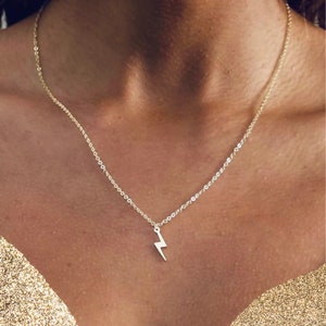 May include: A gold chain necklace with a small lightning bolt pendant.