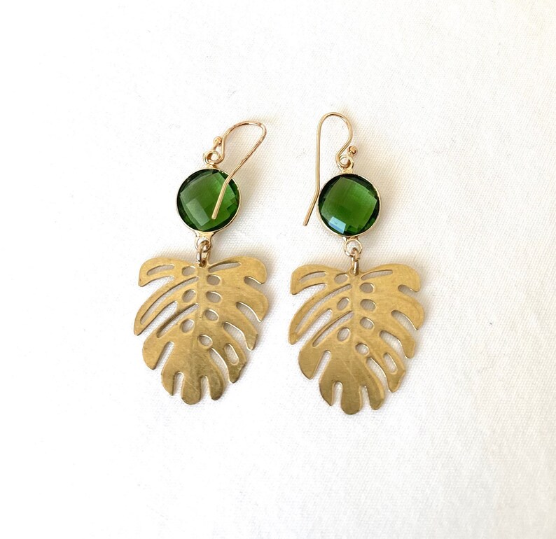 May include: Gold earrings with green gemstone accents and a cutout monstera leaf design.