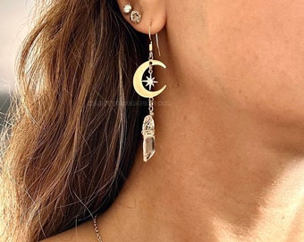 May include: Gold crescent moon earrings with a small star and a clear quartz crystal dangle. The earrings are labeled "North Star drop".