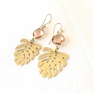 May include: Gold earrings with a pink gemstone and a cutout leaf design.