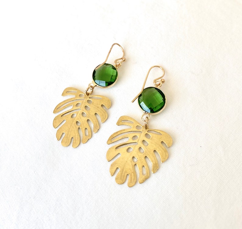 May include: Gold earrings with green gemstone accents and a cutout leaf design.