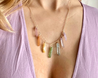 May include: A gold chain necklace with multiple dangling crystal points in various colors, including pink, orange, yellow, green, and blue.