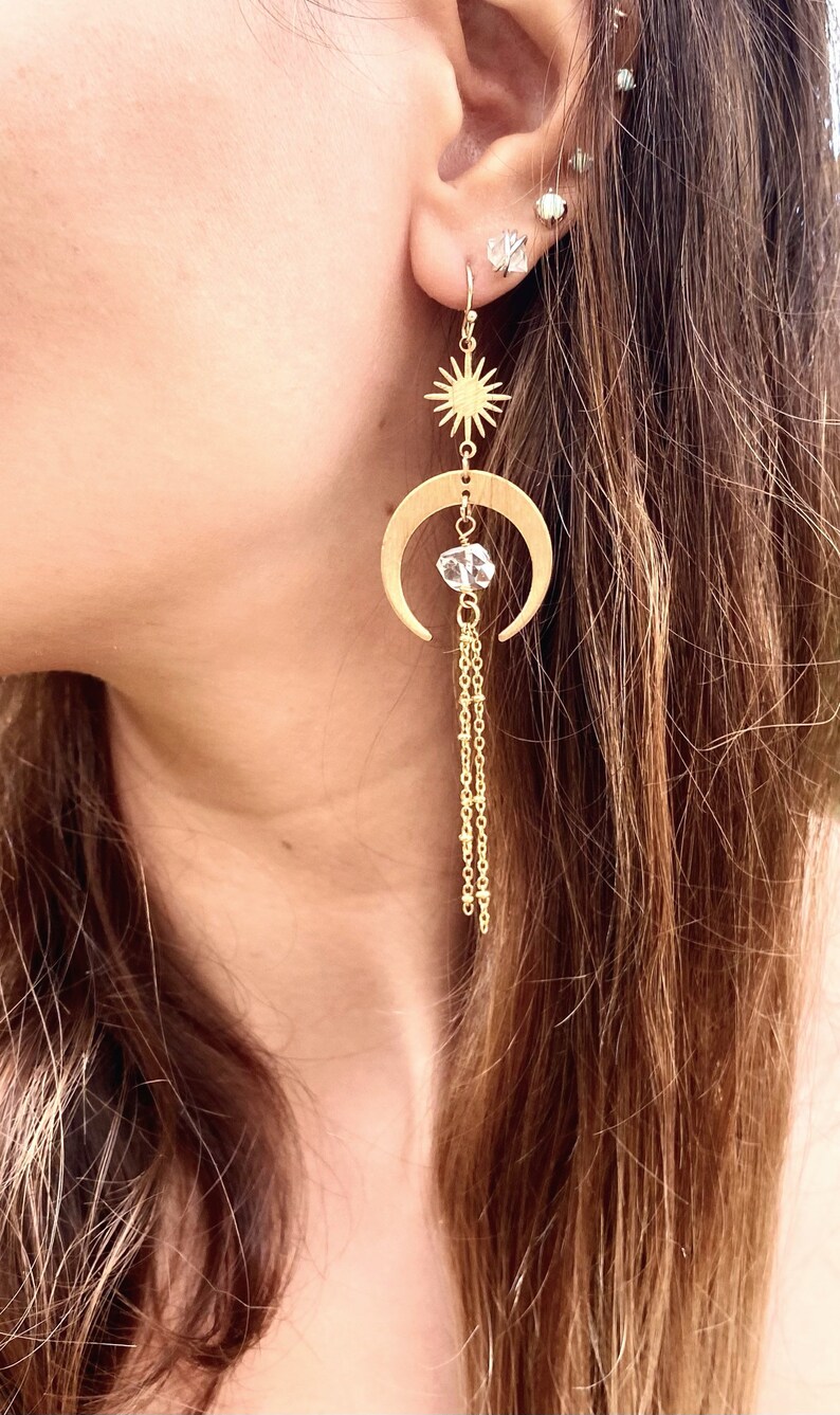 May include: Gold crescent moon earrings with a star charm and a crystal bead dangling from a chain.