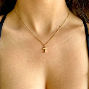 May include: A gold chain necklace with a small gold cross pendant.