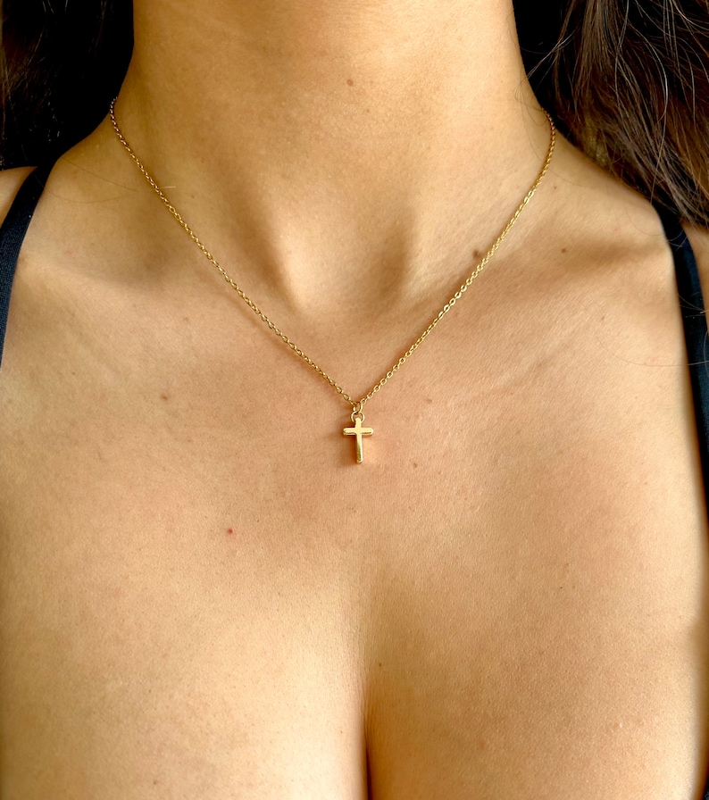 May include: A gold chain necklace with a small gold cross pendant.