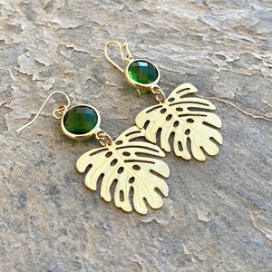 May include: Gold earrings with green gemstone accents and a cutout leaf design.
