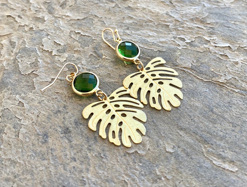 May include: Gold earrings with green gemstone accents and a cutout leaf design.