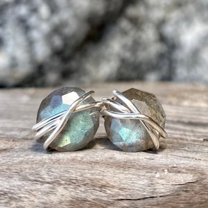 May include: A pair of silver wire wrapped earrings with iridescent blue-green labradorite gemstones.