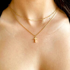 May include: A gold chain necklace with a small gold cross pendant.