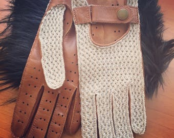 May include: A pair of brown leather driving gloves with a beige knitted back. The gloves have a strap with a button closure on the back of the hand.