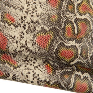 Könnte beinhalten: Nahaufnahme eines strukturierten Schlangenhautmusters. Das Design weist eine Mischung aus Farben auf, darunter Weiß, Schwarz, Rot und Gelb. Das Muster ist detailliert und scheint auf einem flexiblen Material zu sein, möglicherweise Leder oder Stoff.