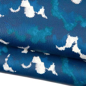 May include: Close-up of a textured, blue material with a pattern of white and blue cloud-like shapes. The material is folded over, revealing the underside. The overall effect is a modern, abstract design.
