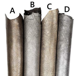 May include: Four vertical rolls of textured leather labeled A, B, C, and D. Roll A is bronze, B is silver, C is gold, and D is a metallic grey. Each piece features a consistent, fine, diamond-shaped embossed pattern across the entire surface.