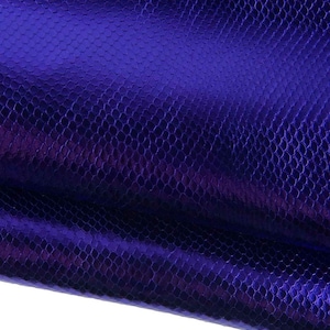 Puede incluir: Una lámina de material morado vibrante con una textura distintiva y repetitiva similar a la piel de serpiente. La superficie tiene un brillo metálico y reflectante que capta la luz, creando variaciones sutiles en la profundidad del color violeta.